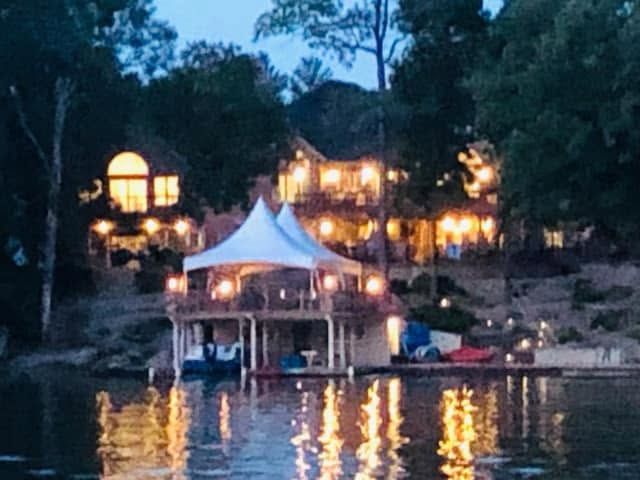 High-peak tent lit up on a boat dock at dusk