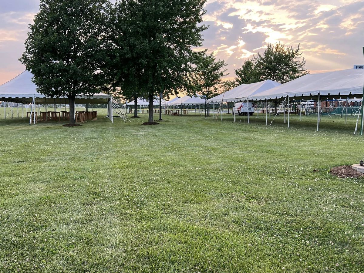 Pole tents on a lawn under a sunset sky