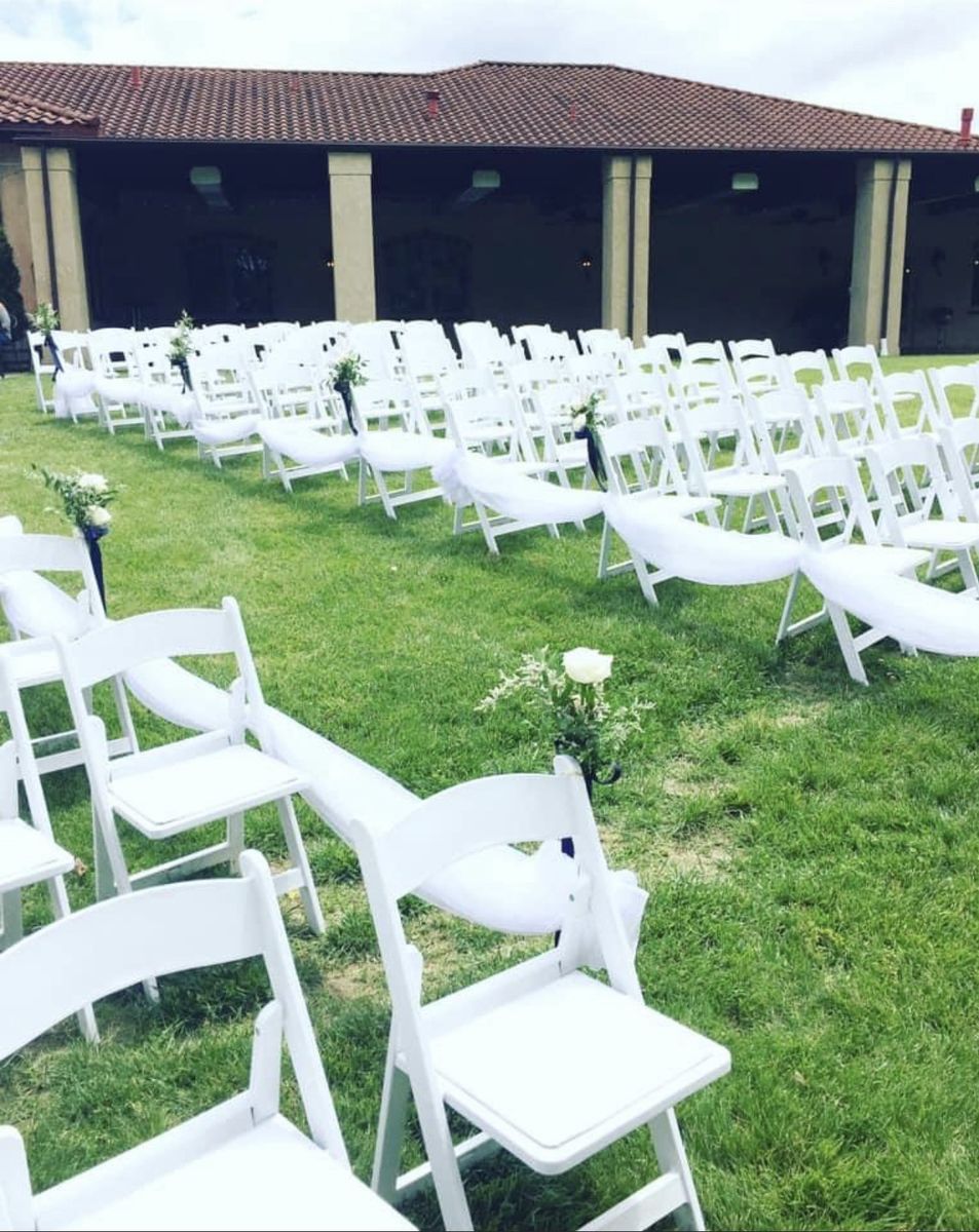 White padded garden chairs set in rows for an outdoor wedding ceremony